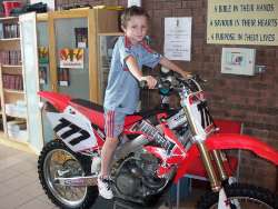 Young Lewis Beattie hitches a ride on a motor bike belonging to Holy Trinity parishioner David Mulligan a parishioner who does motocross and trials riding.
